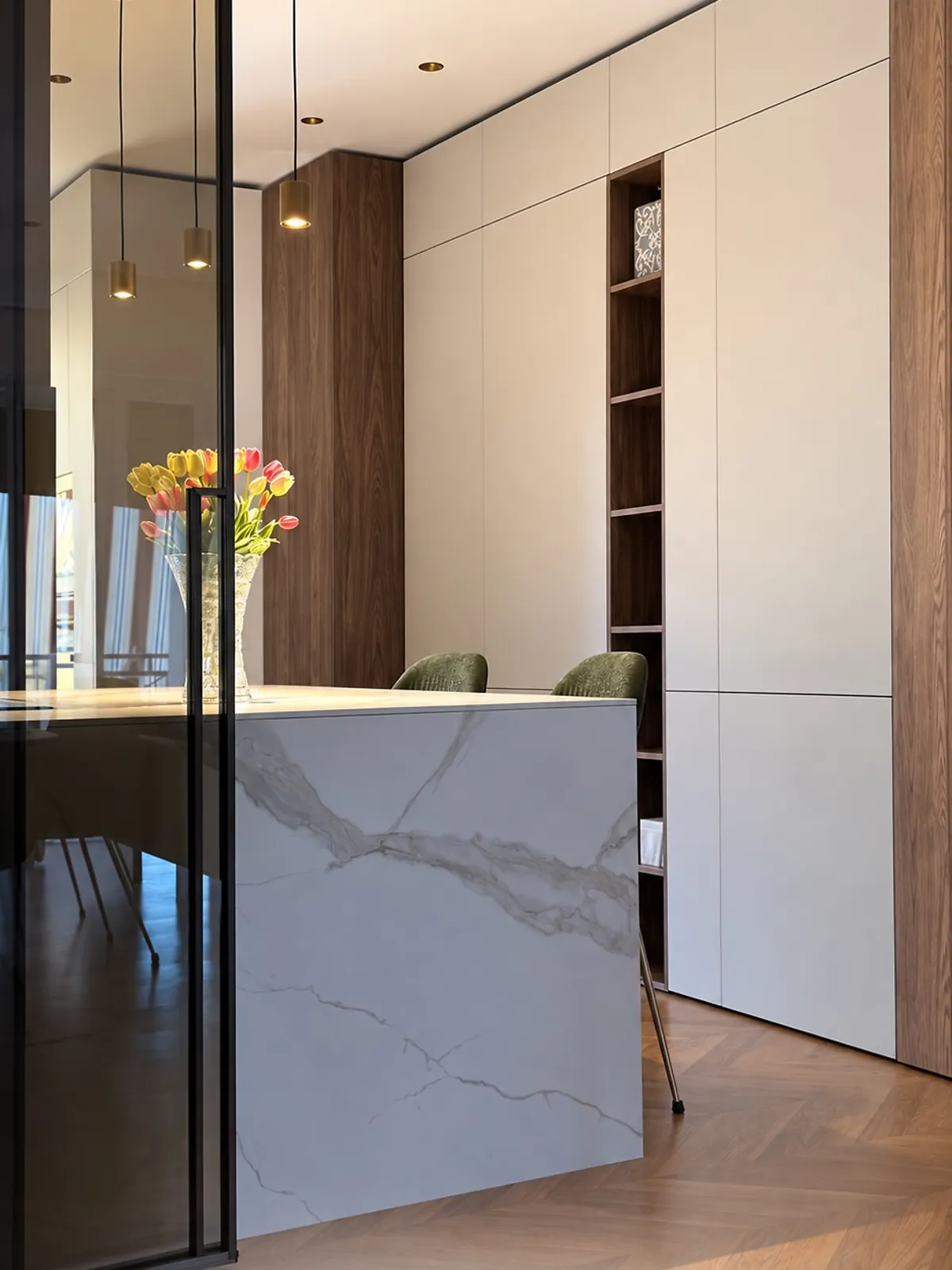 Isola in gres effetto marmo, colonne bianche e noce, parquet a spina e lampade a sospensione ottone